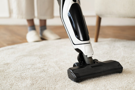 A homeowner maneuvering a lightweight sweeper on a carpet.