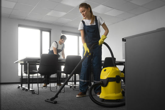 Janitor using a wet dry vacuum in a commercial space.